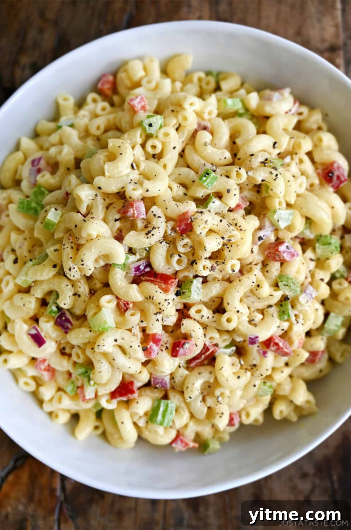 A big white serving bowl containing macaroni salad.