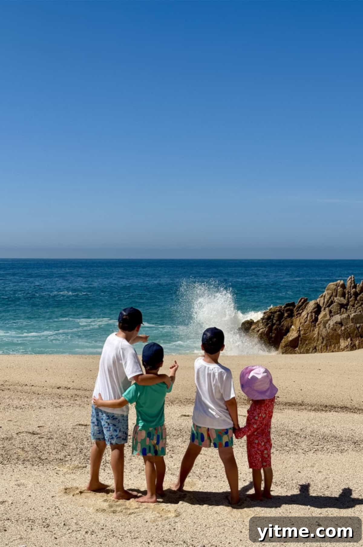 Four kids standing on a beach pointing at crashing waves - Capturing the joy of childhood exploration by the sea.