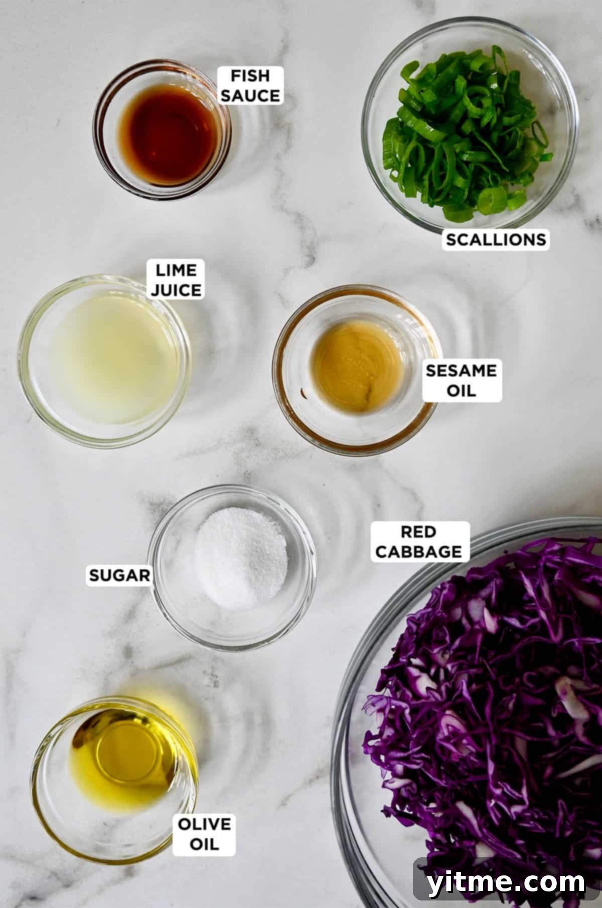 A collection of fresh ingredients for Asian slaw in glass bowls, including vibrant shredded purple cabbage, rich olive oil, granular sugar, aromatic sesame oil, savory fish sauce, tangy lime juice, and finely chopped scallions.