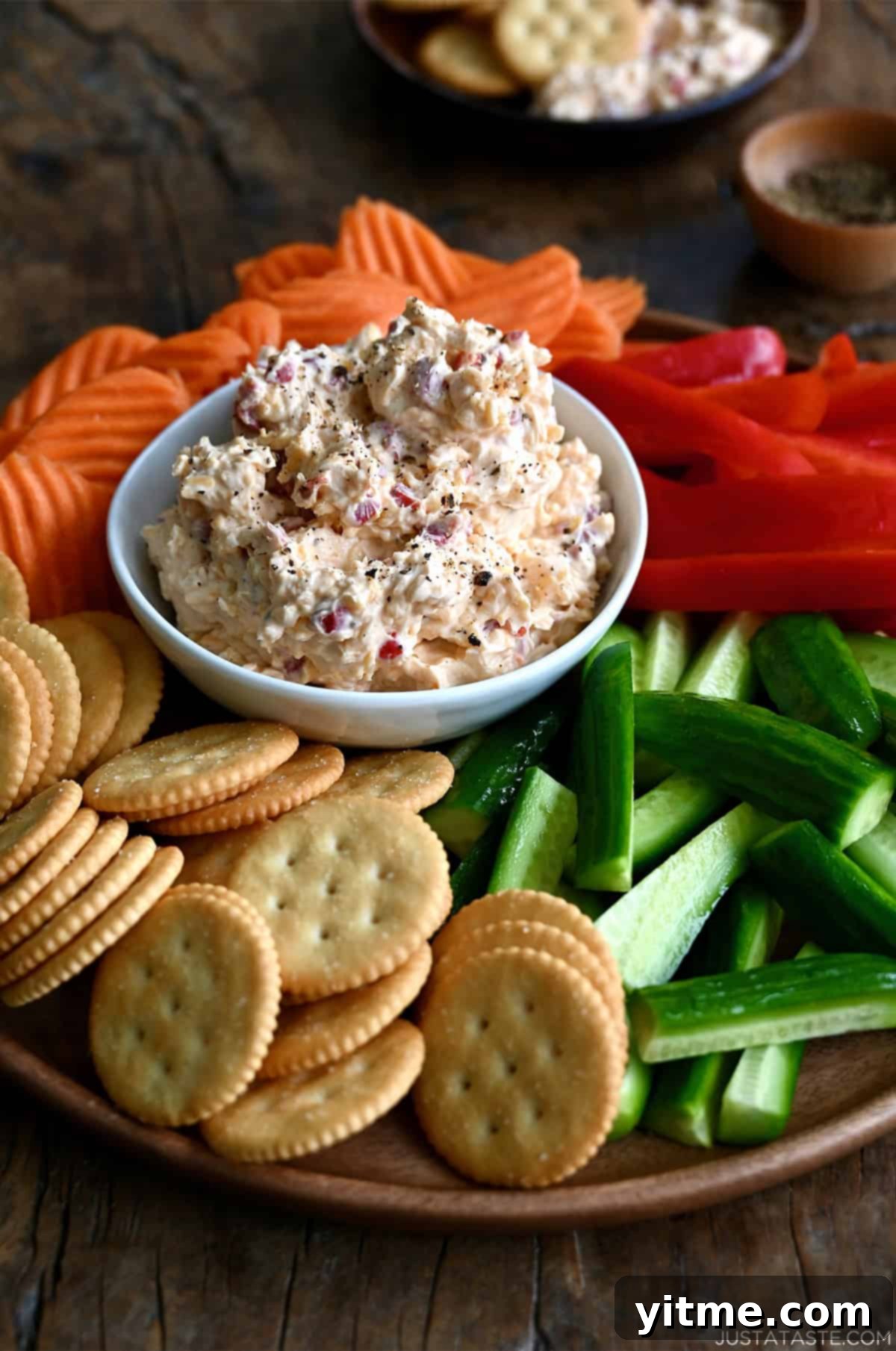 Pimento cheese dip in a small bowl surrounded by vegetables and crackers