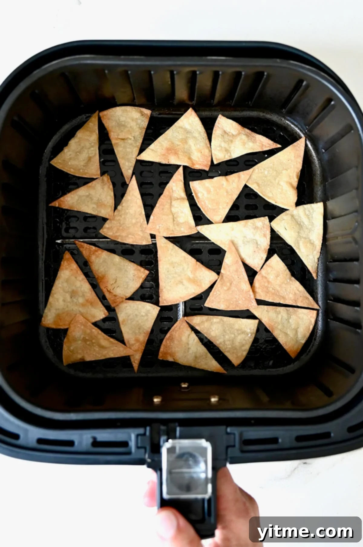Crispy Homemade Tortilla Chips: Two Ways to Deliciousness 7 Air fryer tortilla chips in the basket of an air fryer.