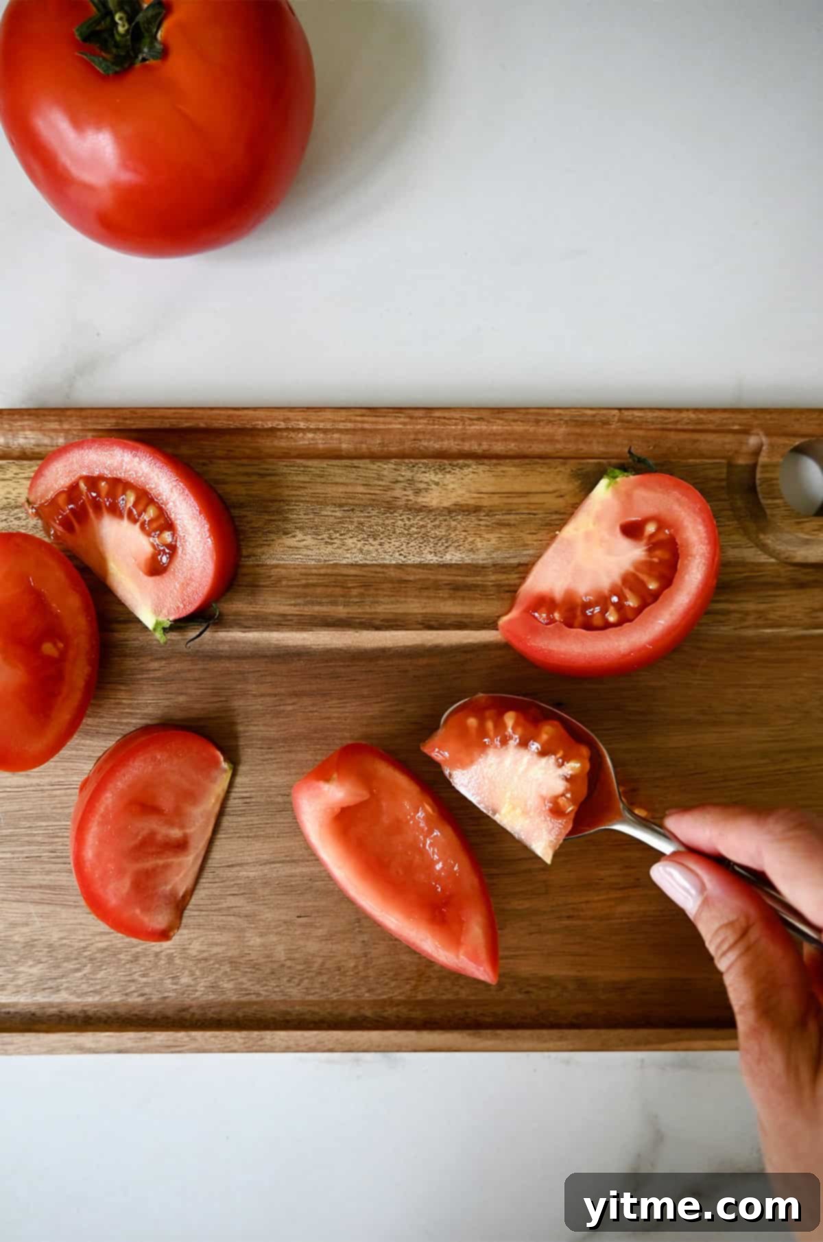 Coring and scooping out the seeds from a Roma tomato.