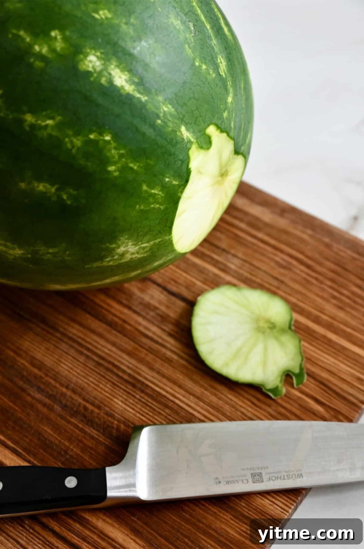 Slicing the base of a watermelon off to make it sit level.