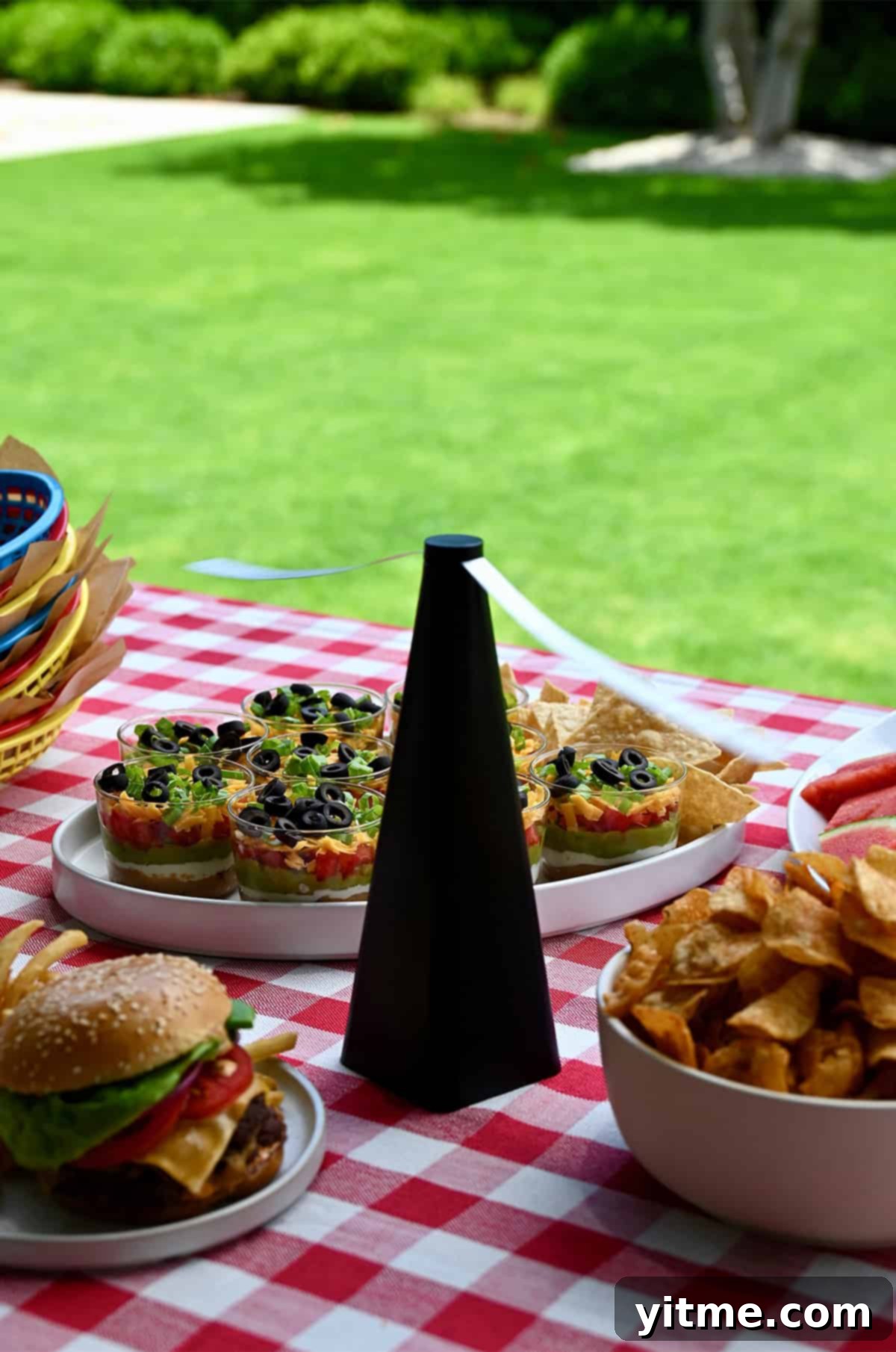 Bug-repelling fan on an outdoor dinner table with classic picnic foods.