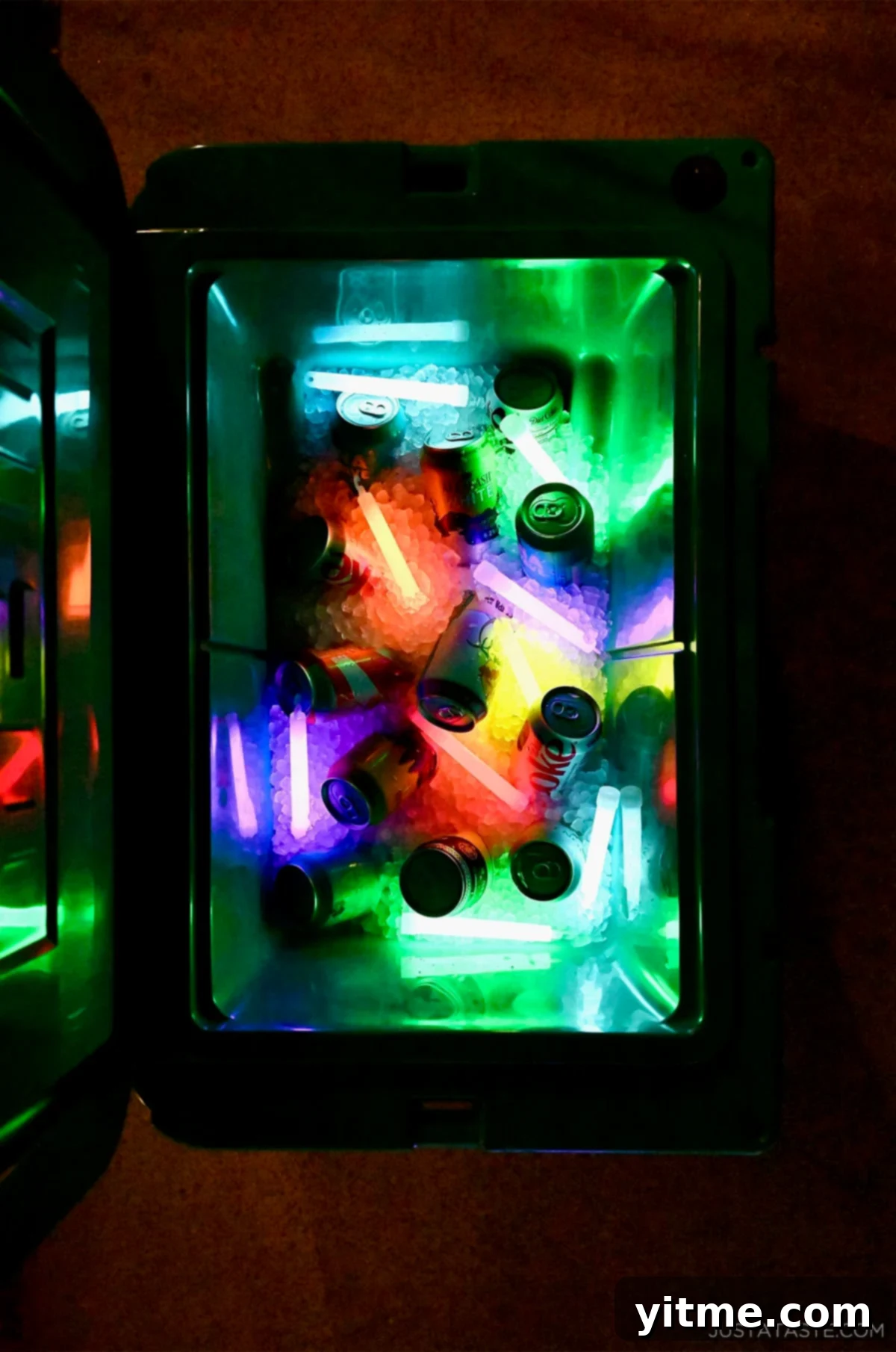 A cooler with ice, soda cans and glow sticks.