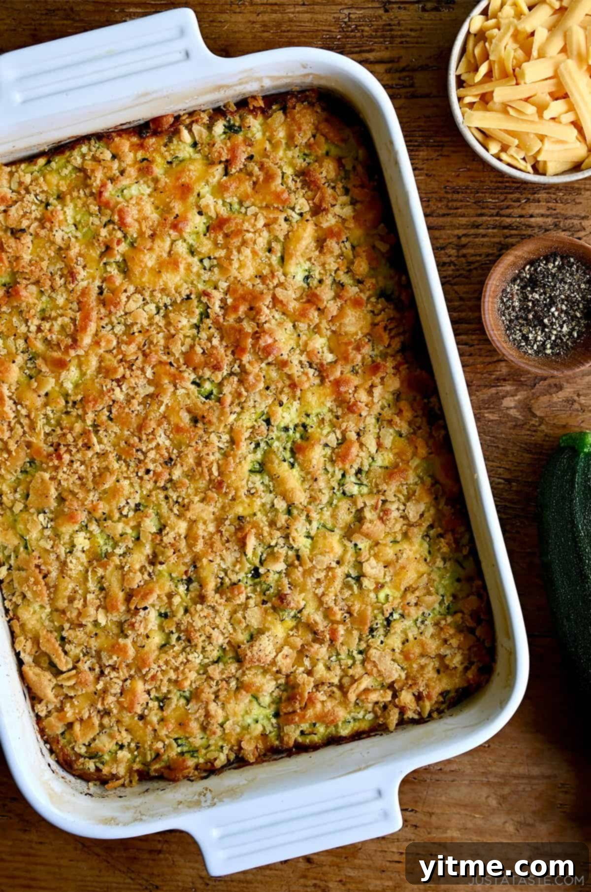 A shredded zucchini casserole with a cracker topping in a white baking dish.