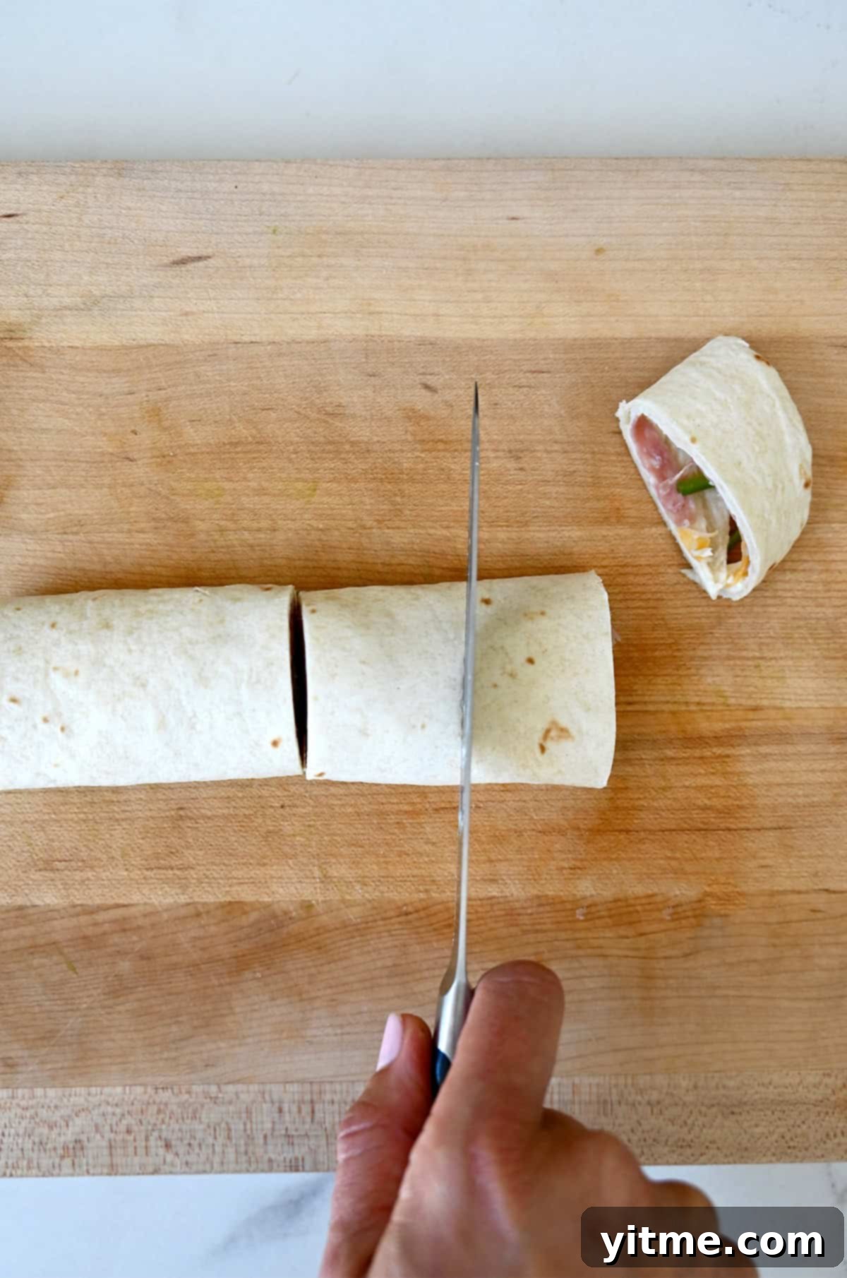 Swirl Sandwiches 7 Cutting a tortilla roll-up into pinwheel sandwiches.