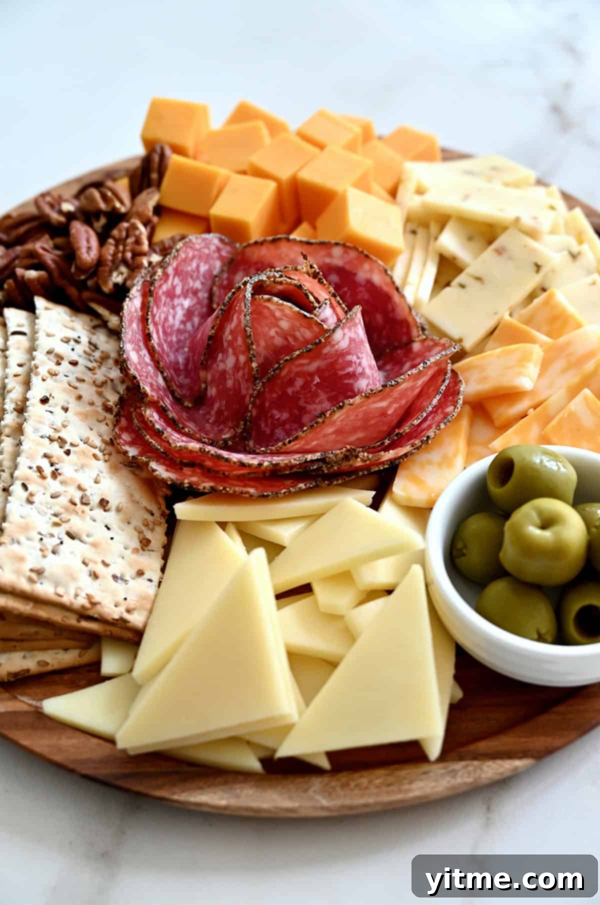 A beautifully crafted salami rose on a charcuterie board, artfully surrounded by a vibrant variety of cheeses, crackers, and olives, showcasing exquisite detail. 