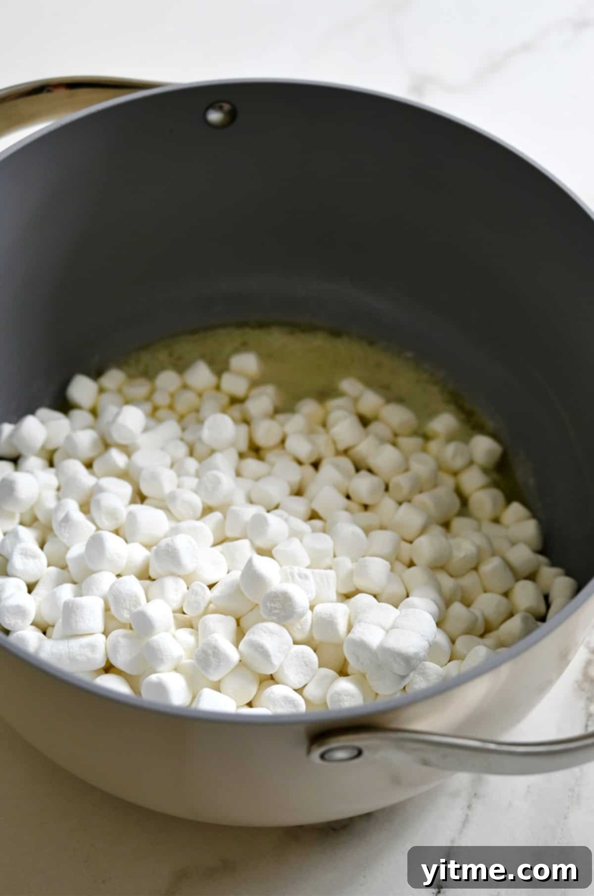 Melting butter and mini marshmallows in a large stockpot.