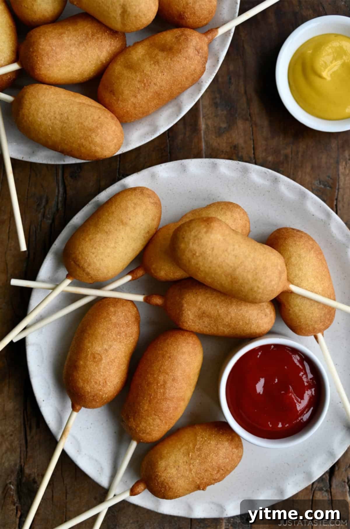 Homemade mini corn dogs on a plate with a small bowl containing ketchup.