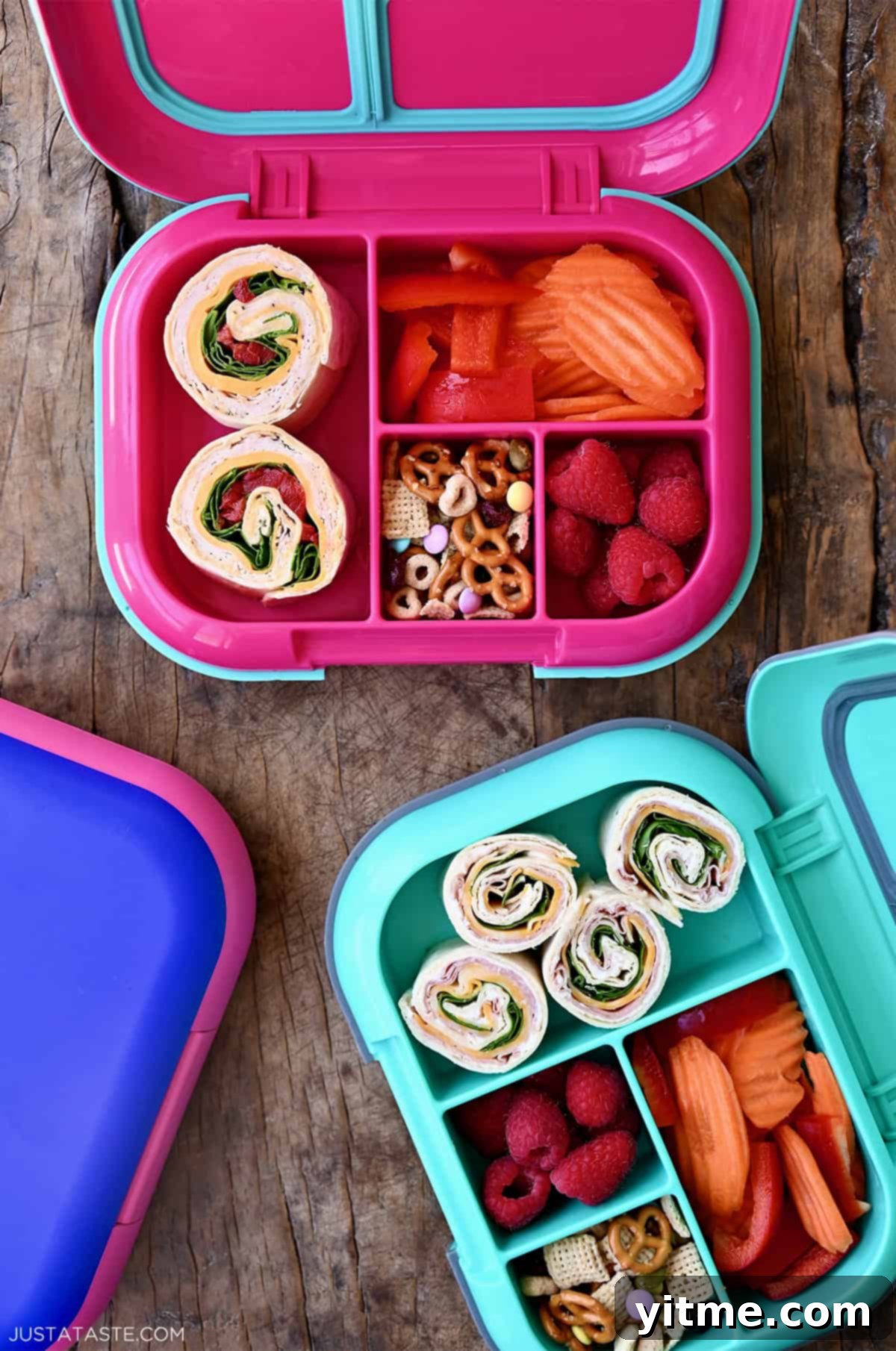 Two lunchboxes containing pinwheel sandwiches, fresh fruit and veggies, and trail mix.