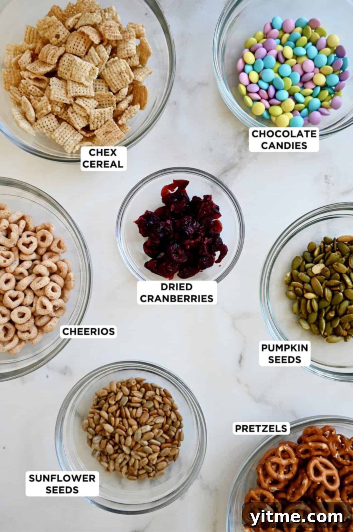 Ingredients to make a school-friendly trail mix: Cheerios, Chex Cereal, M&Ms, dried cranberries, pumpkin seeds, mini pretzels and sunflower seeds.