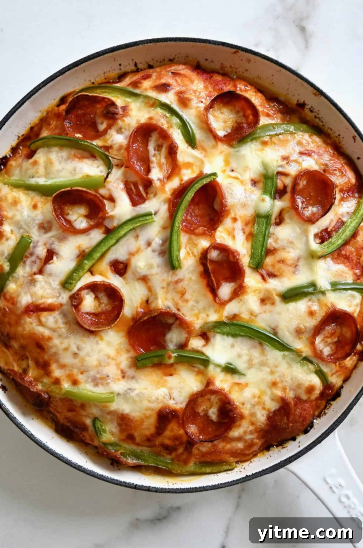 A perfectly baked pepperoni and green pepper skillet pizza, showcasing a crispy, golden brown crust and melted cheese, ready for serving.