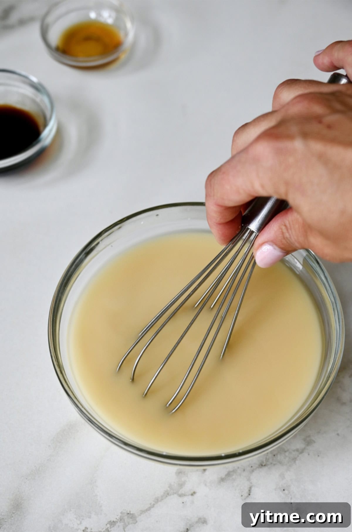 Whisking cornstarch and chicken stock together in a small ceramic bowl to create a smooth slurry.