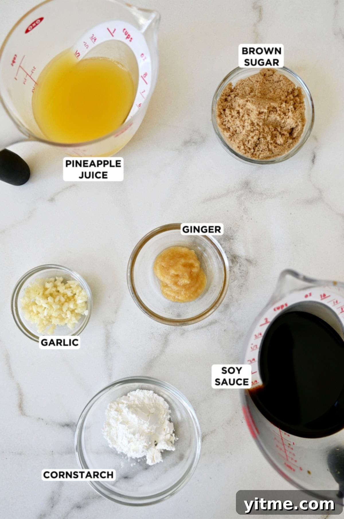 The six essential ingredients laid out for making homemade teriyaki sauce: low sodium soy sauce, pineapple juice, brown sugar, minced garlic, minced ginger, and cornstarch slurry.