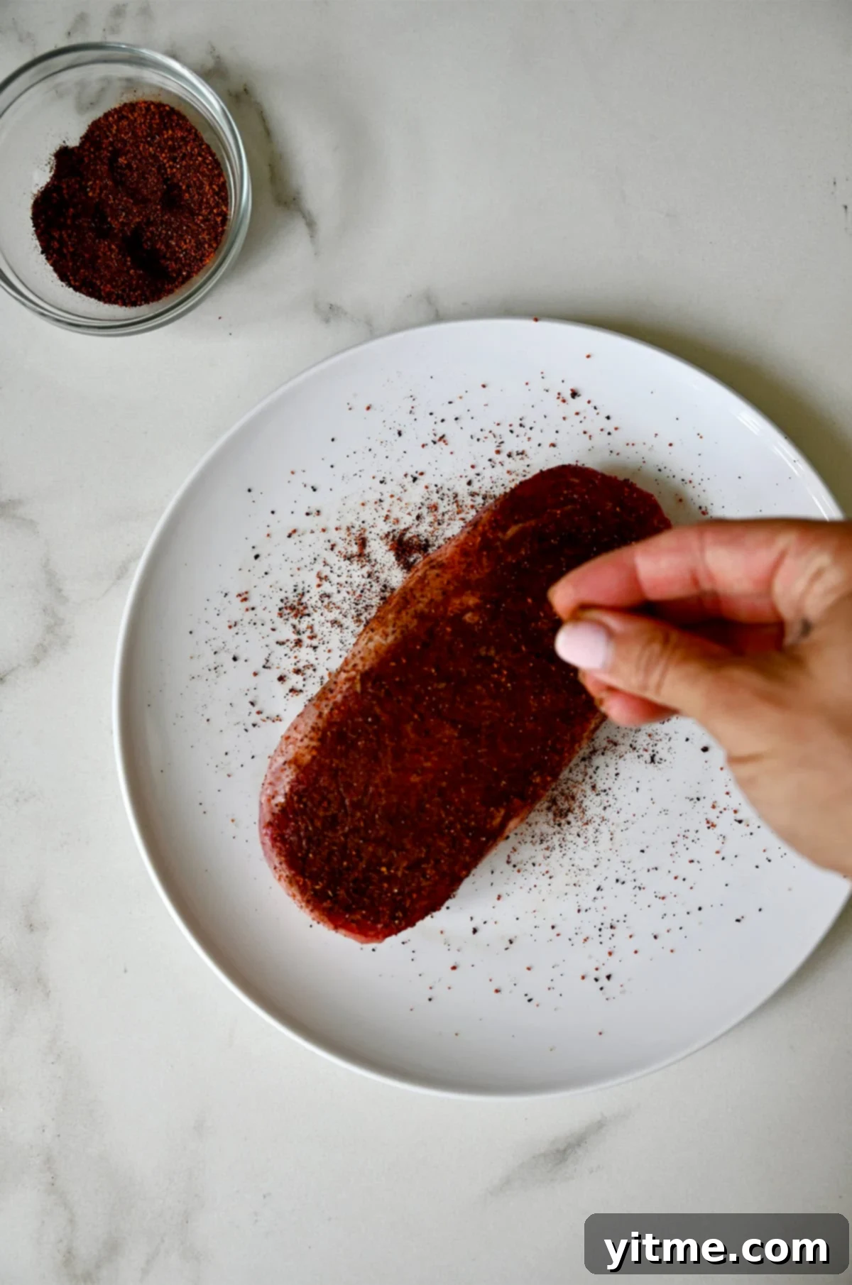 Seasoning a well-marbled steak generously with coffee rub and sea salt before searing.