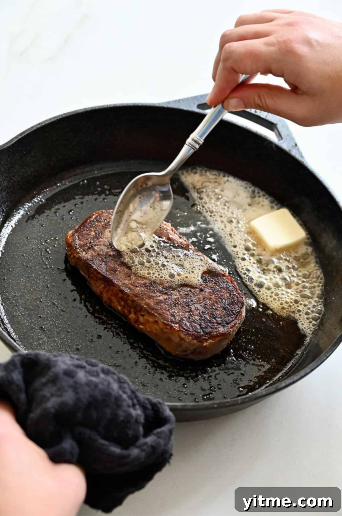 Butter basting steak in a cast iron skillet for added flavor and moisture.