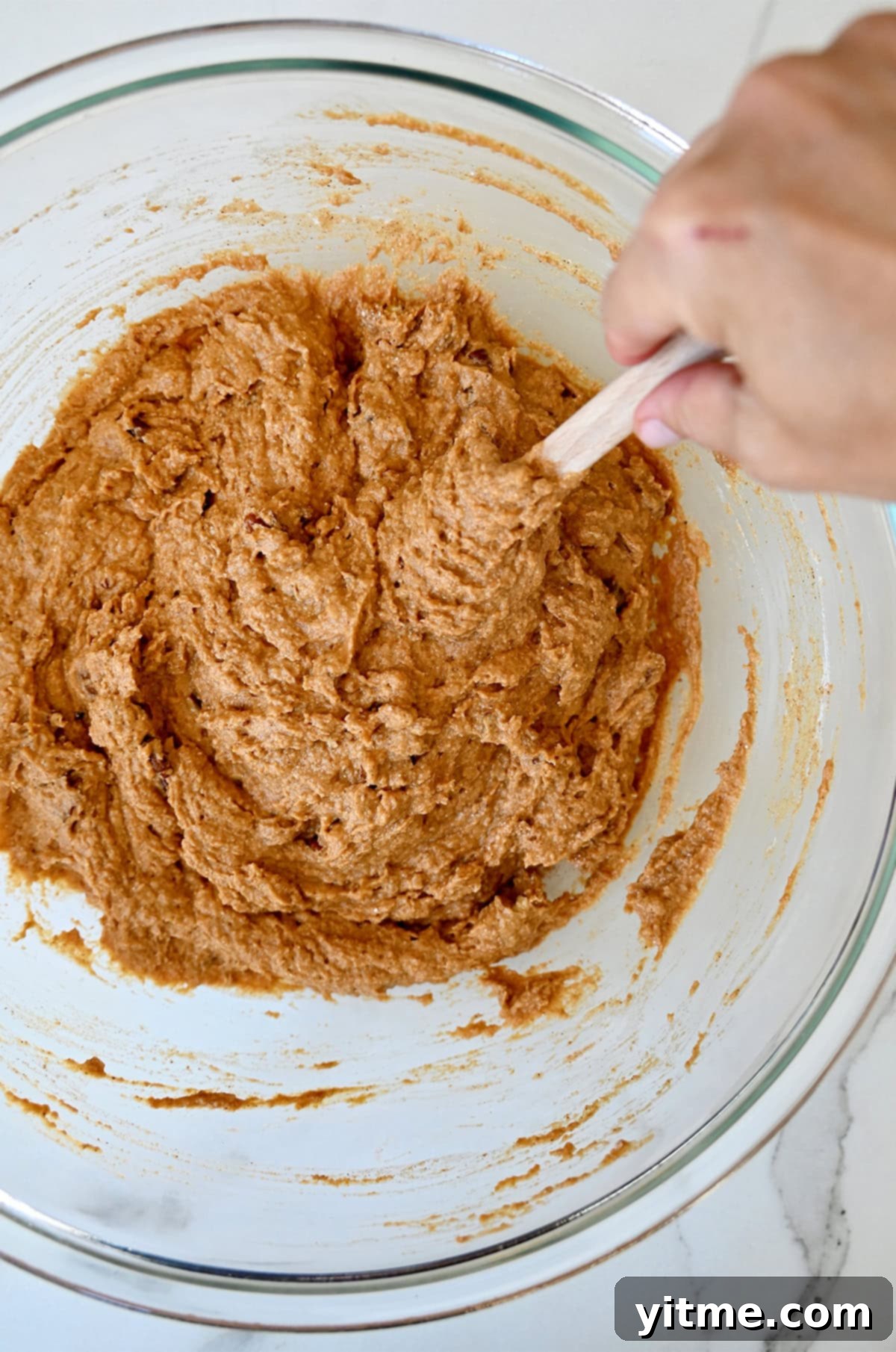 Wholesome Pumpkin Delights 8 A glass bowl holding perfectly mixed pumpkin muffin batter, ready for baking. The batter has a smooth and consistent texture, promising delicious results.