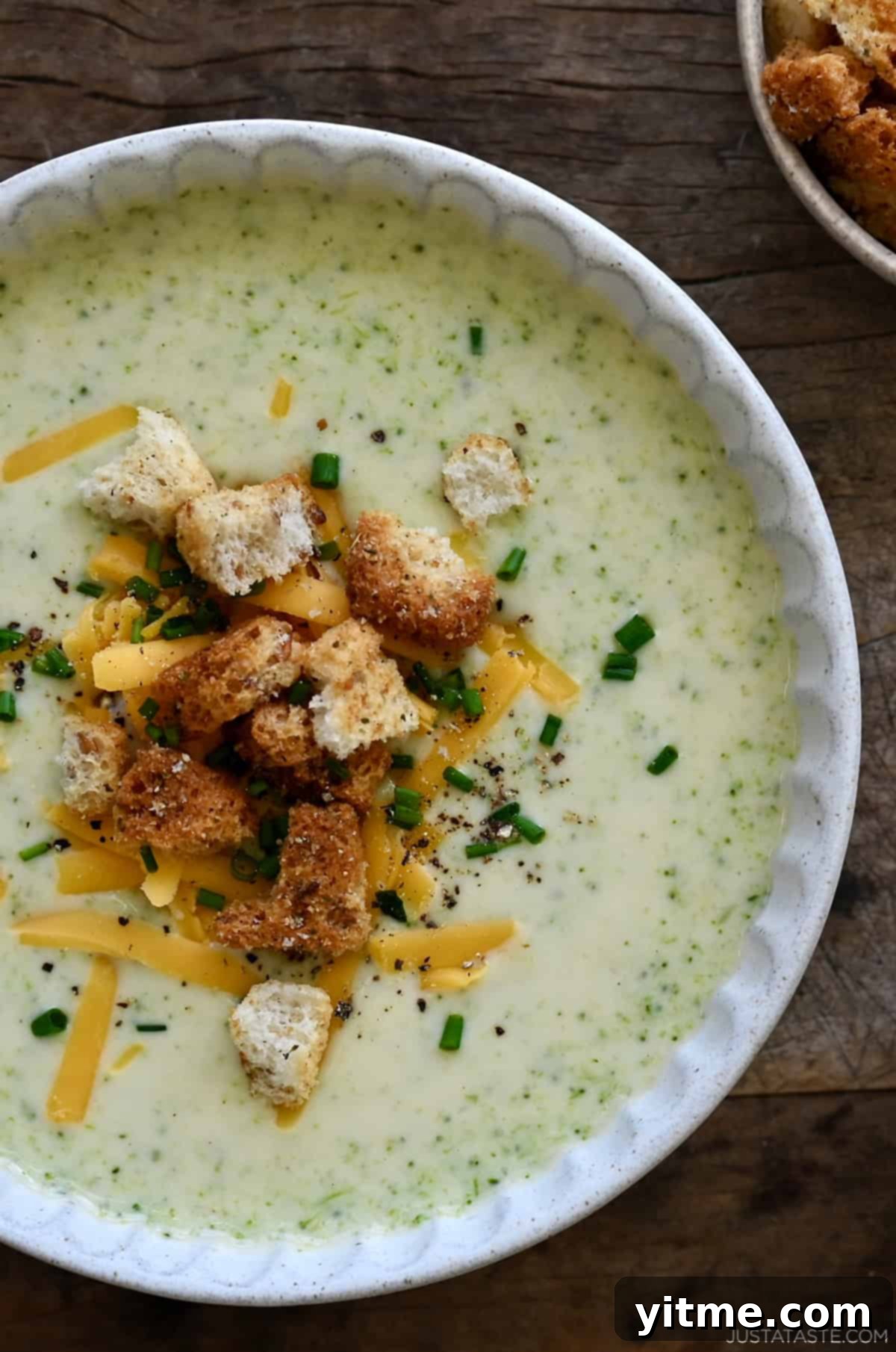 Creamy Broccoli Cheddar Soup 5 A bowl of creamy broccoli cheddar soup topped with croutons, shredded cheese and chopped chives.