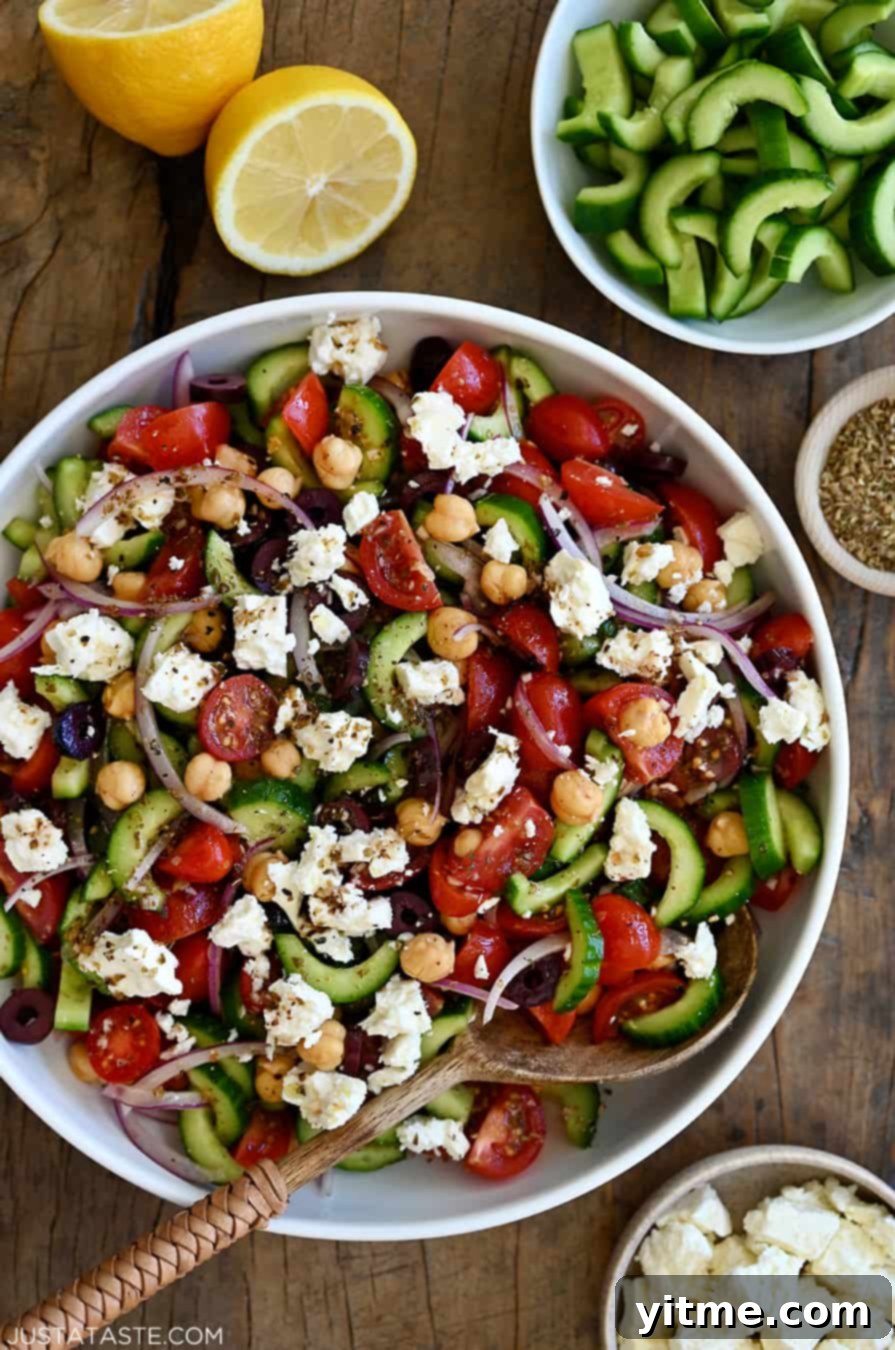 A large serving bowl containing a refreshing Greek cucumber tomato salad with crumbled feta cheese, perfect for a summer gathering.