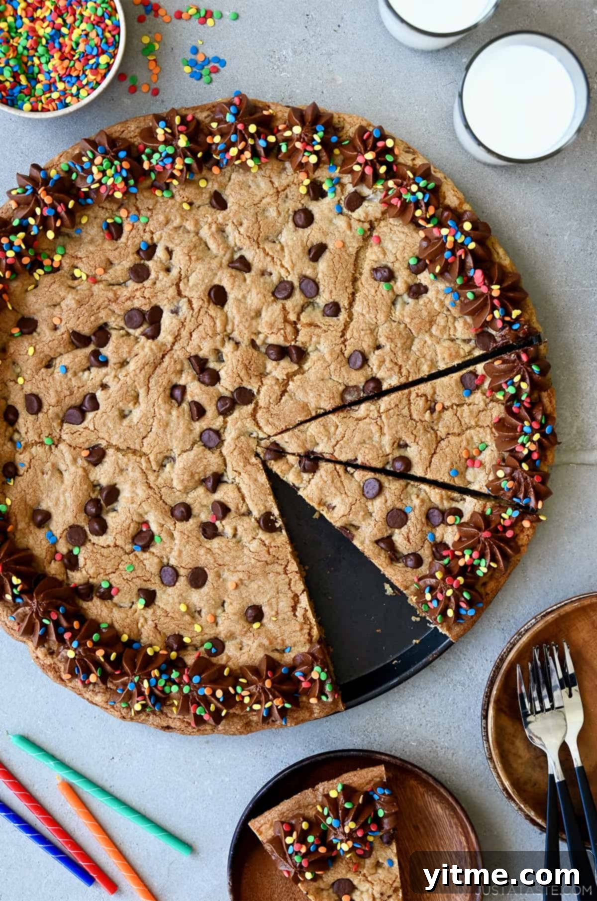 A top-down view of a Giant Chocolate Chip Cookie Cake, decorated with chocolate frosting and festive rainbow sprinkles, perfect for a party.