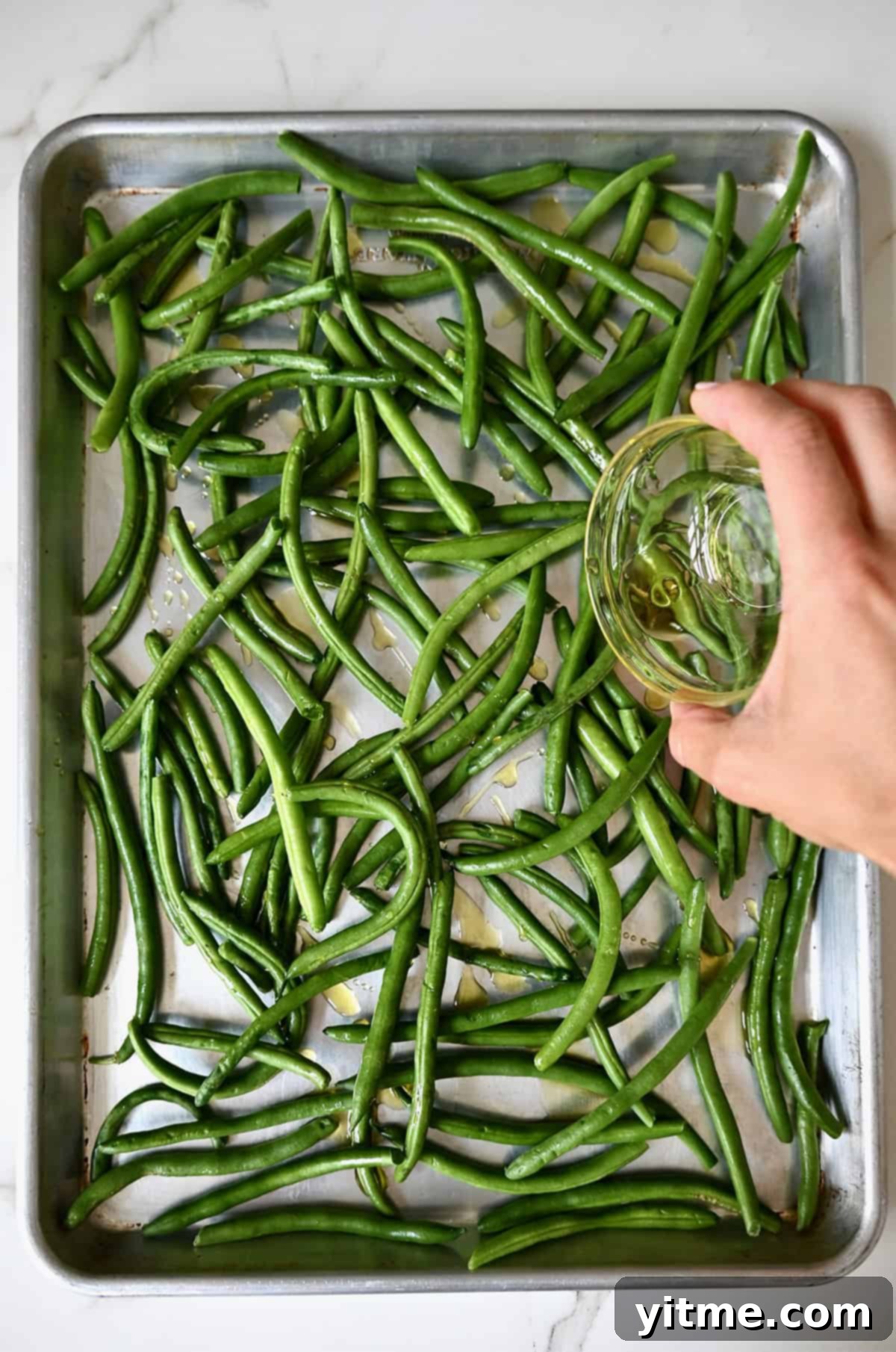 Pouring olive oil on green beans