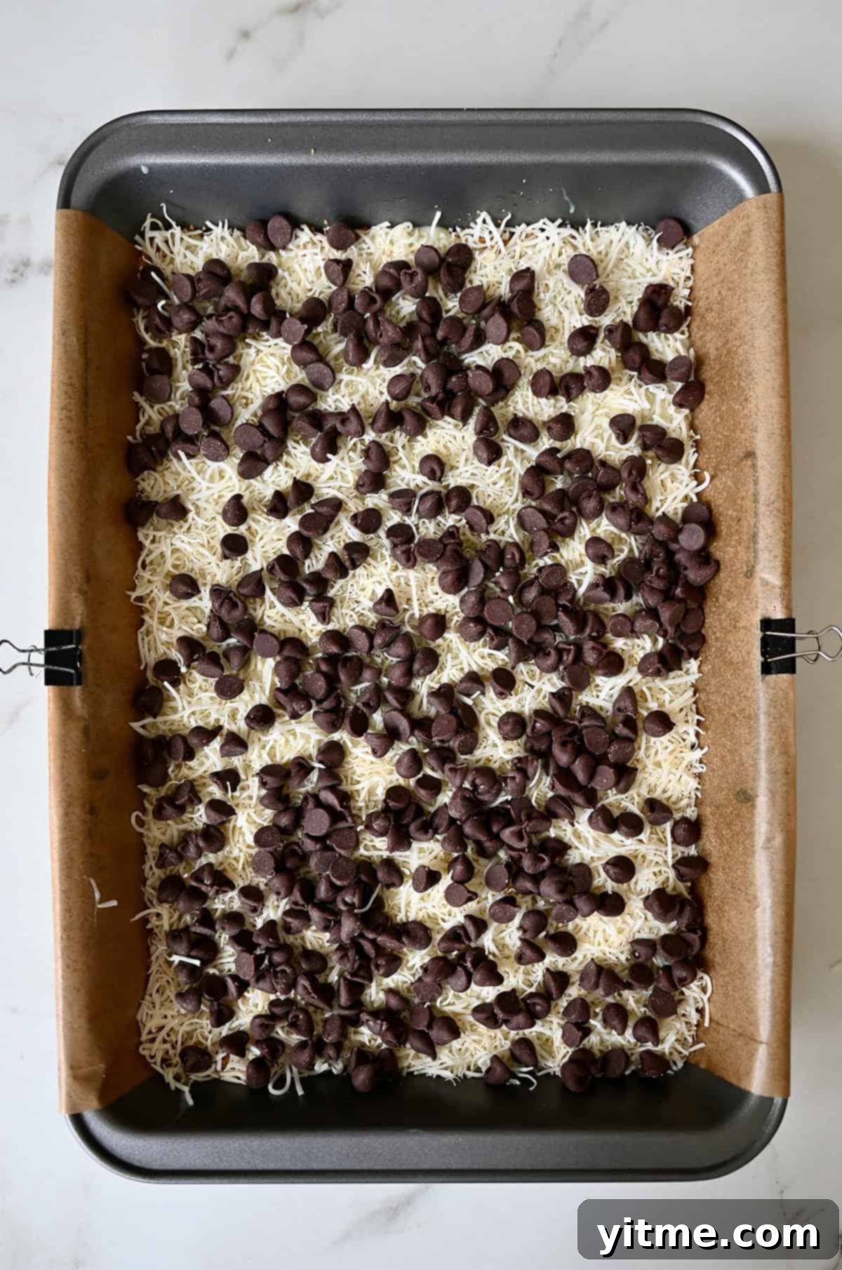 Everything Cookie Bars 11 Adding the chocolate chip layer of magic bars, evenly spread for perfect distribution.