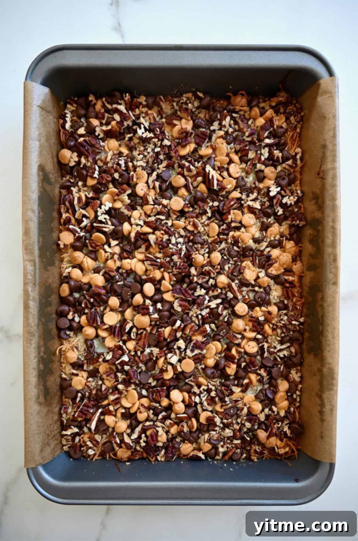 Everything Cookie Bars 13 Freshly baked magic cookie bars, still in the pan, displaying a golden-brown top and gooey layers.