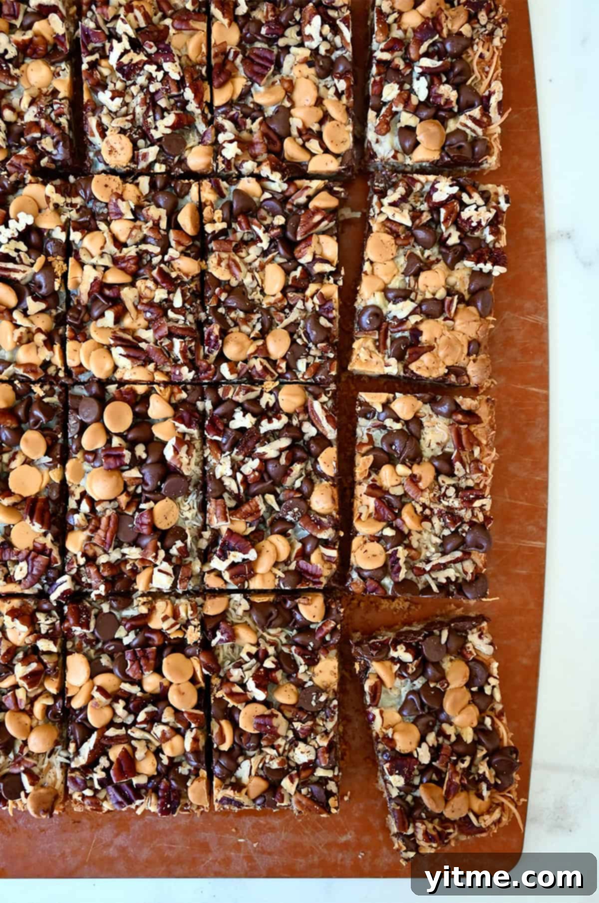 Everything Cookie Bars 5 Magic cookie bars cut into perfect squares on a wooden cutting board, ready to be served.