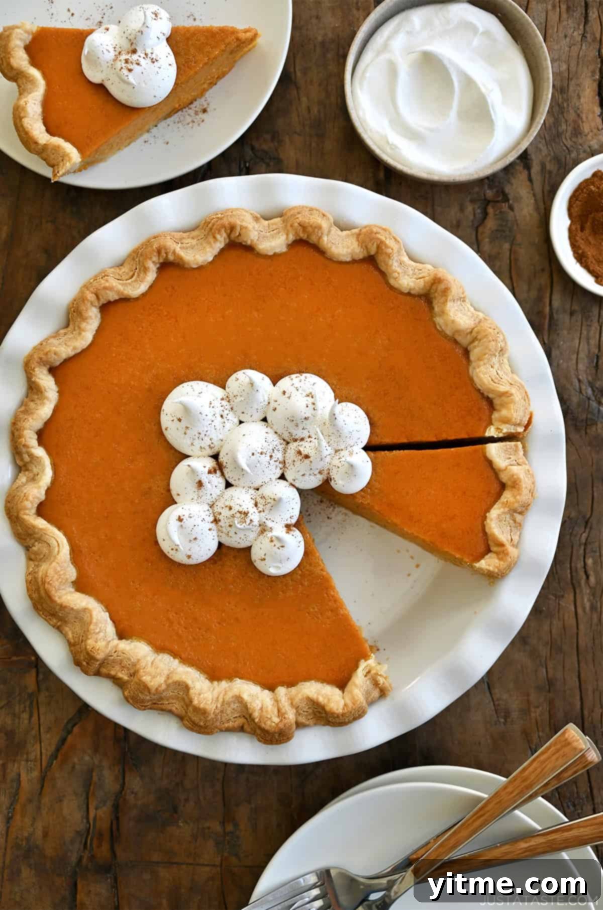 Golden Pumpkin Perfection 11 A stunning homemade pumpkin pie made from scratch, featuring a perfect homemade crust, beautifully topped with generous swirls of whipped cream and a delicate sprinkle of pumpkin pie spice, ready to be enjoyed.