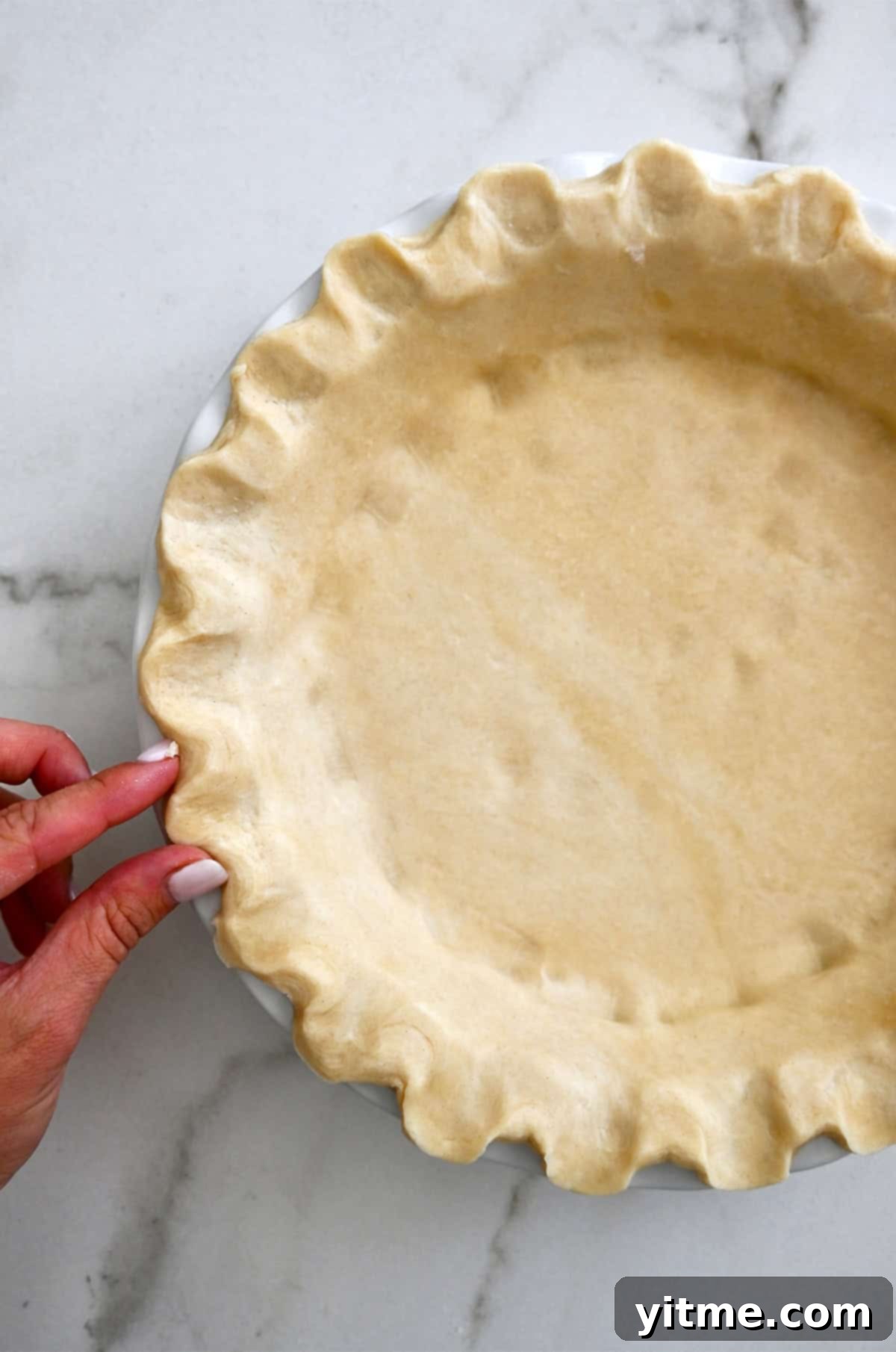 Golden Pumpkin Perfection 5 Hands carefully crimping the edges of a homemade pie crust in a deep pie pan, ready for the filling.