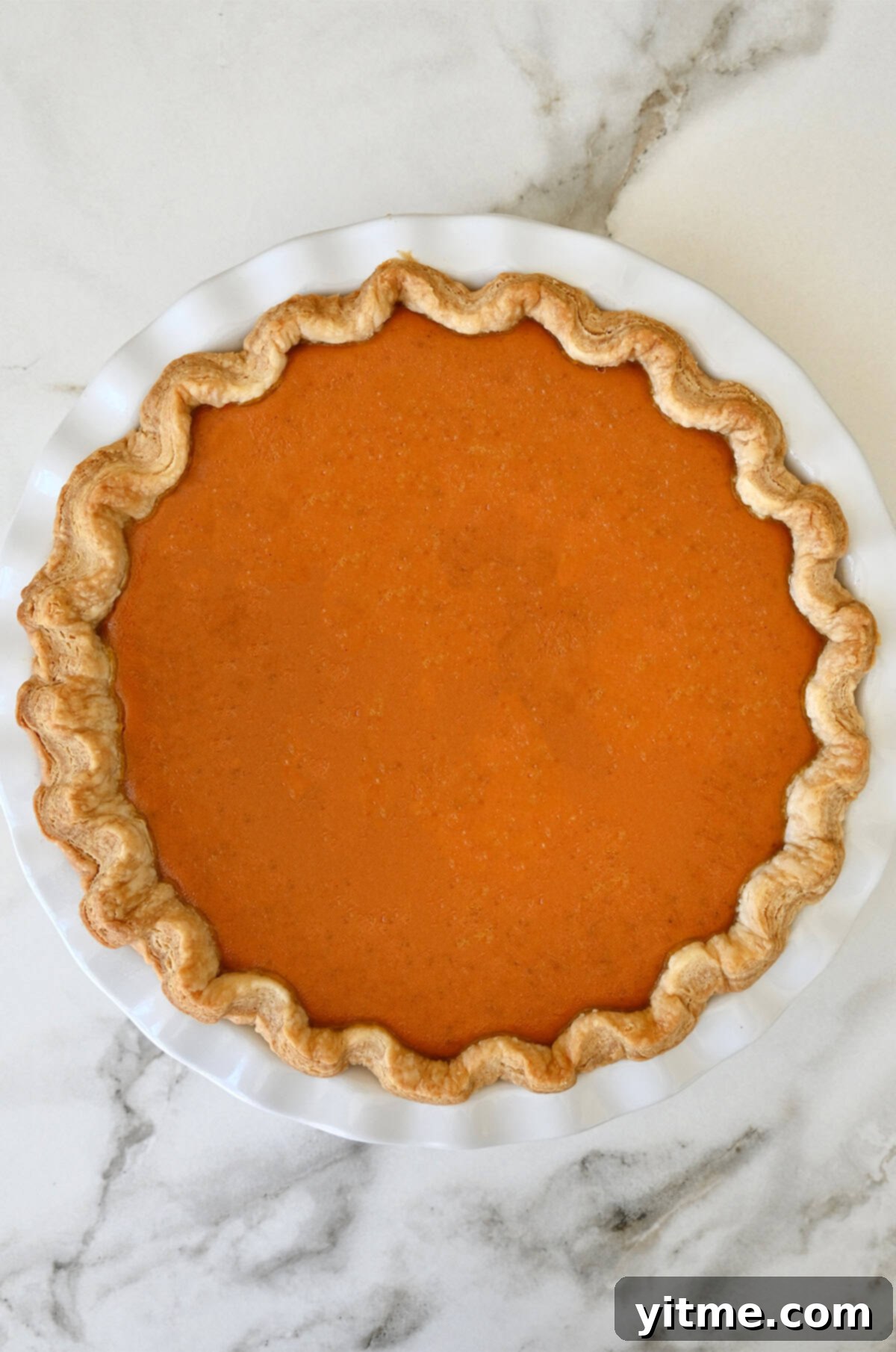 Golden Pumpkin Perfection 10 A freshly baked homemade pumpkin pie with a perfectly smooth, uncracked surface, cooling on a wire rack on a kitchen counter.