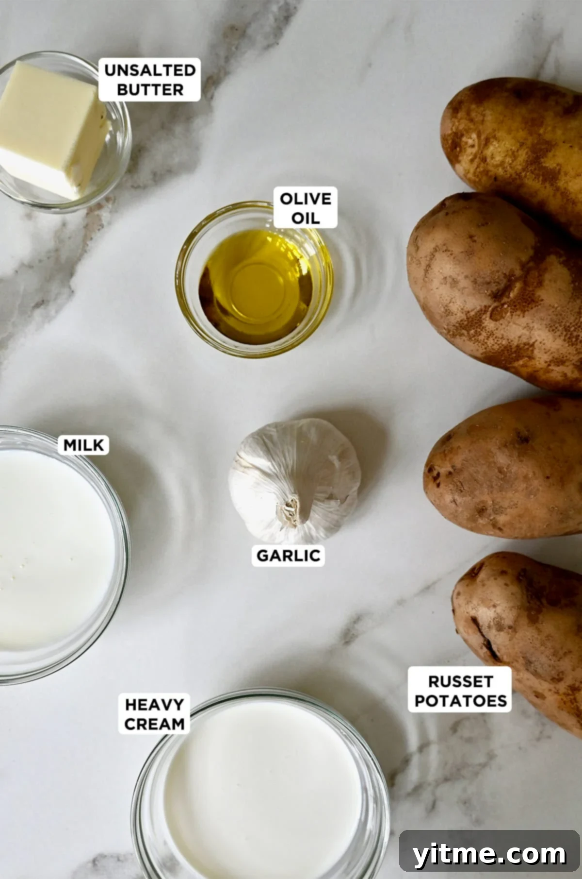Ingredients for roasted garlic mashed potatoes: russet potatoes, garlic, heavy cream, milk, butter, and olive oil.