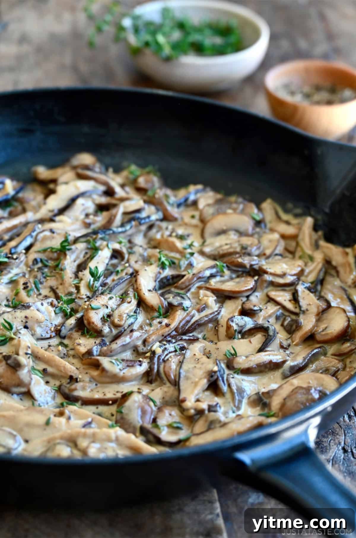 Creamy mushroom sauce garnished with thyme in a large skillet.
