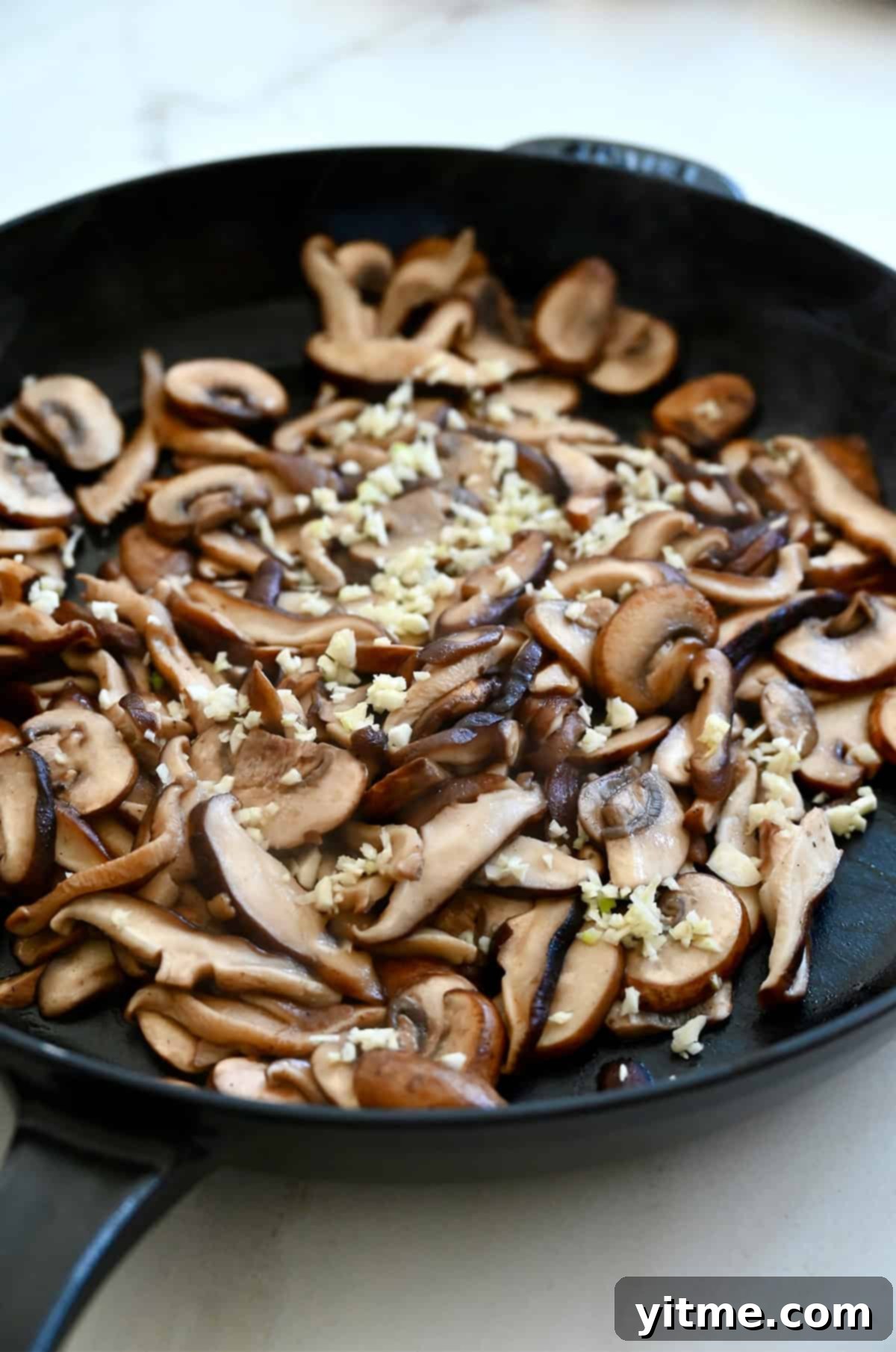 Sautéed mushrooms in a large skillet with garlic.