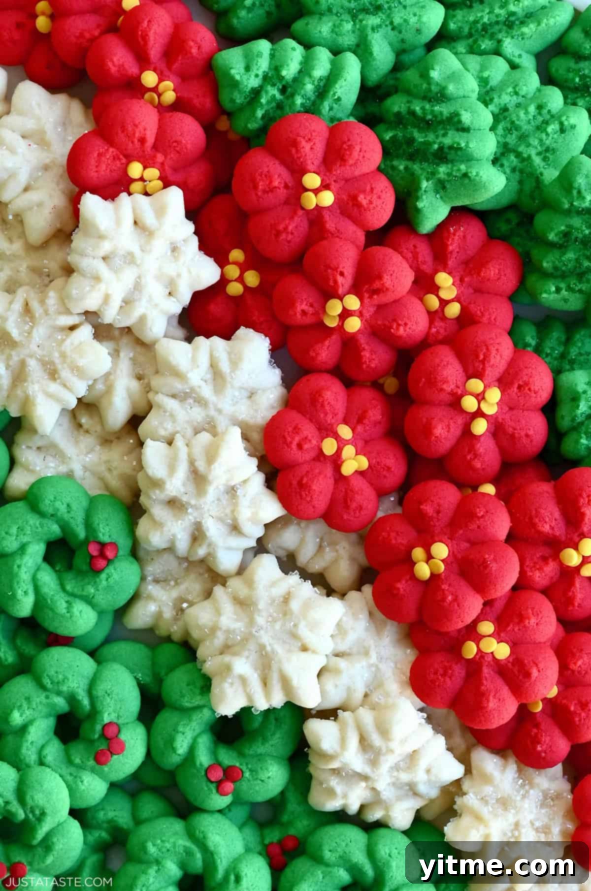 Red and green spritz cookies, along with snowflake-shaped spritz cookies, arranged beautifully on a plate.