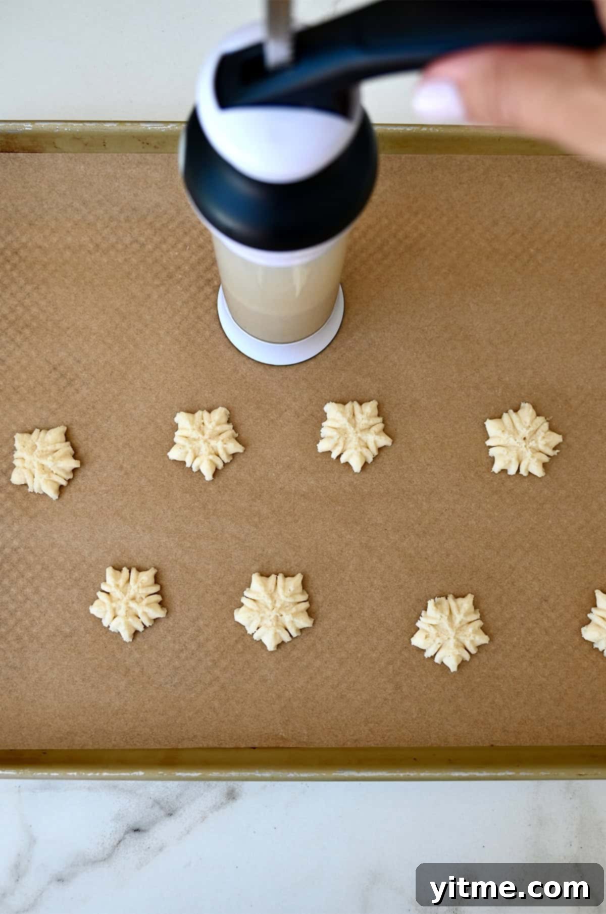 Using a cookie press to shape spritz cookies.