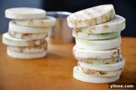 Frying eggplant rounds in a skillet, turning golden brown for sliders.