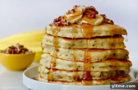 Fluffy Banana Nut Pancakes 3 A white plate containing banana nut pancakes topped with syrup