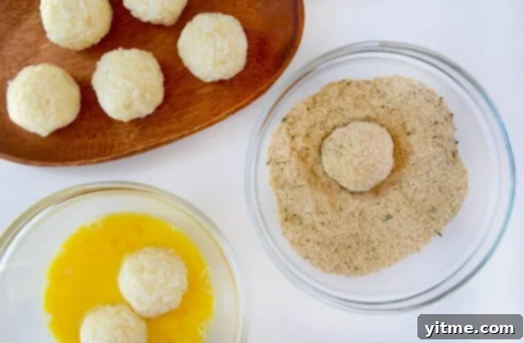 Hands dipping arancini in eggs and breadcrumbs before frying