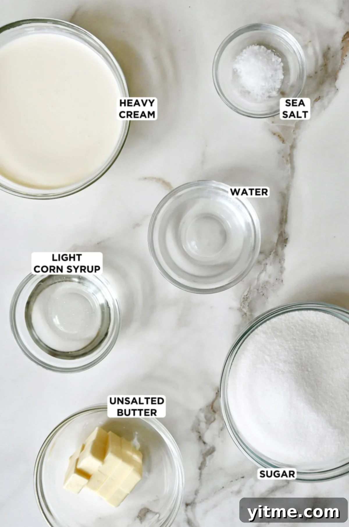Various sizes of glass bowls containing heavy cream, sea salt, water, sugar, unsalted butter and light corn syrup.