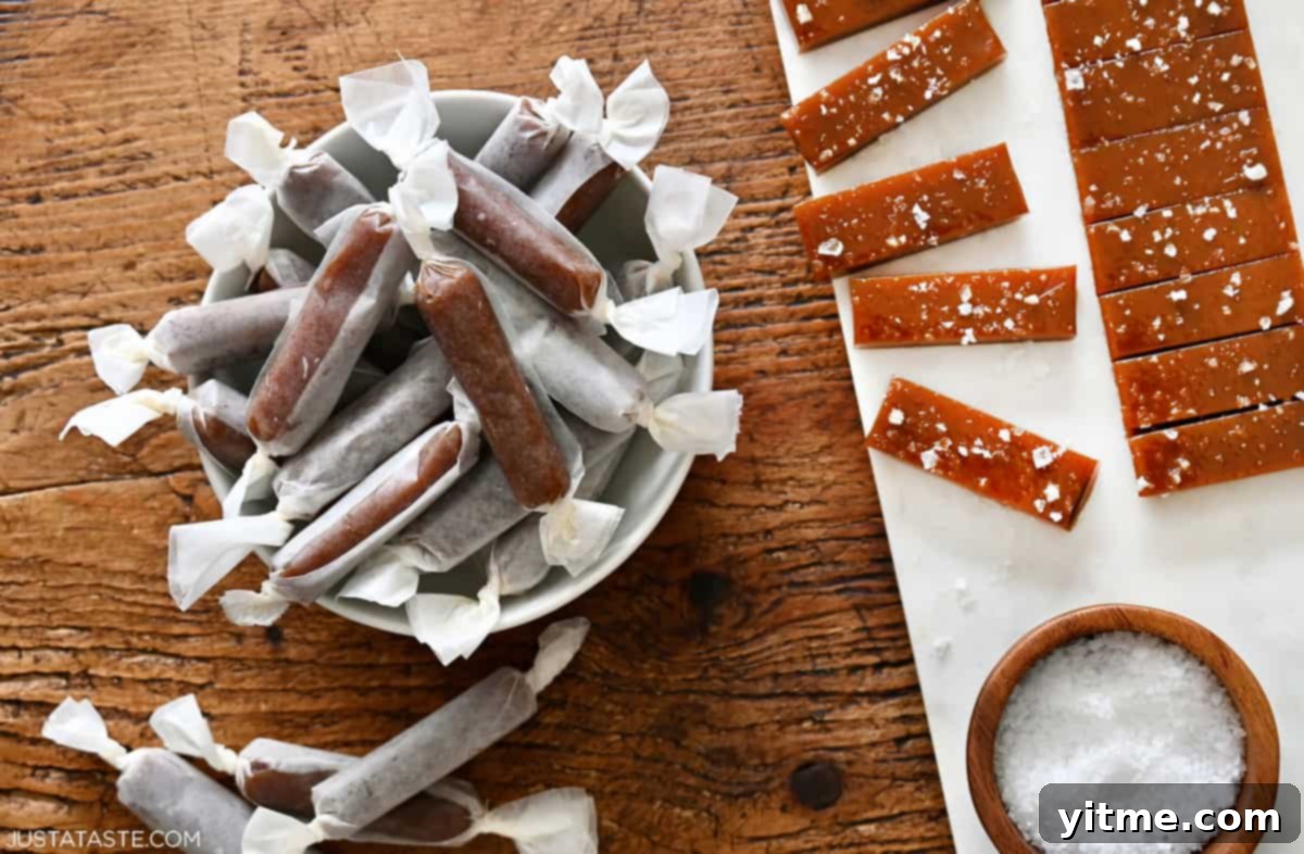 Soft homemade caramels wrapped in wax paper next to more that haven't been wrapped yet.