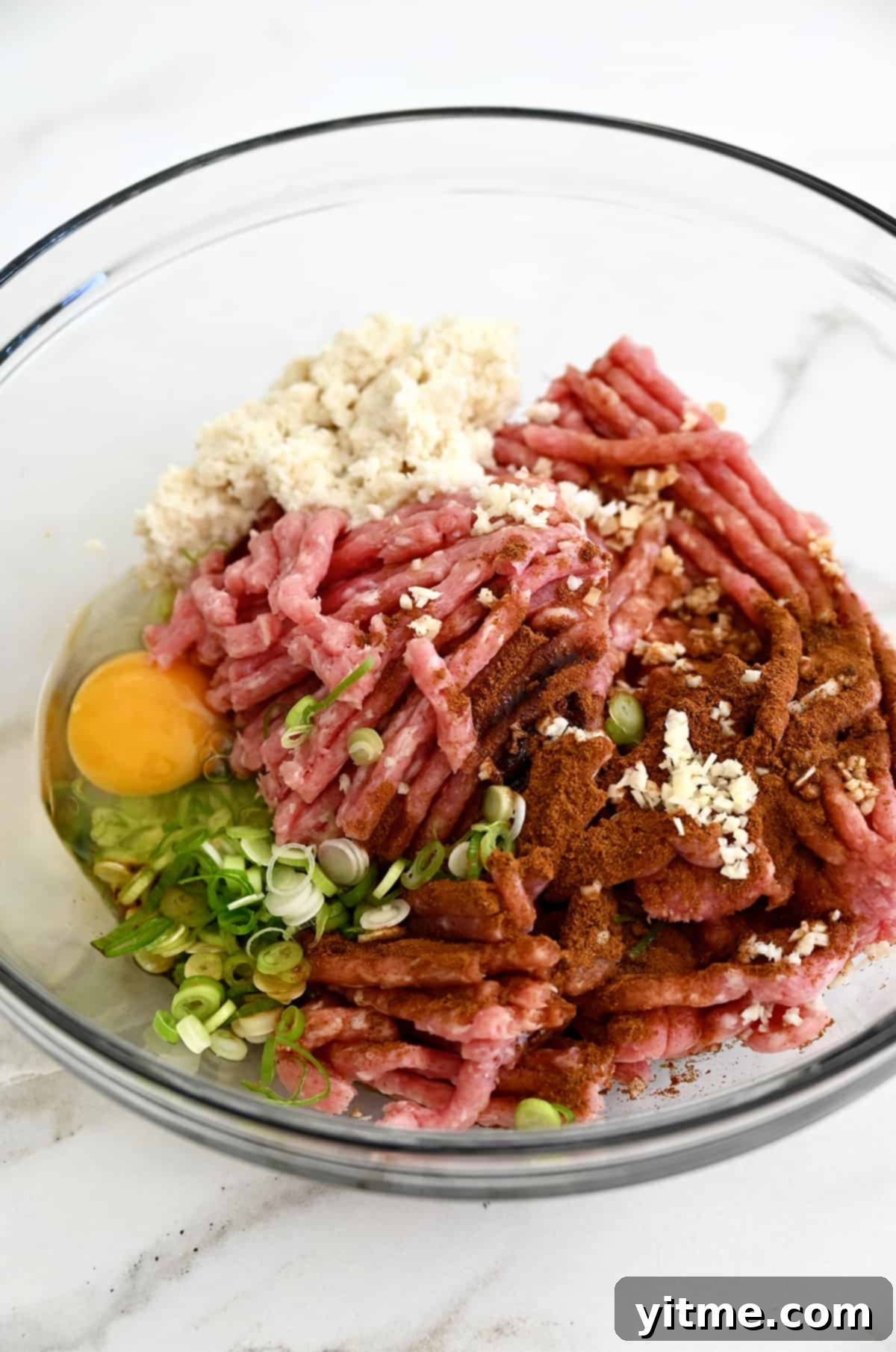 Ground pork, scallions, egg, Chinese 5 spice, and panko breadcrumbs in a clear bowl.